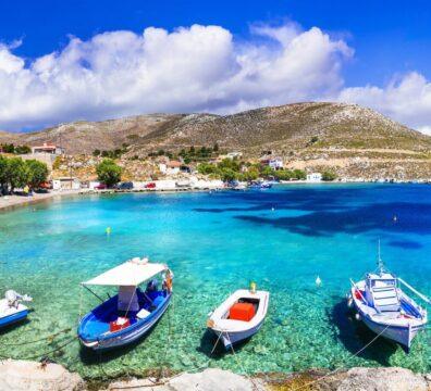 Blue and white Greek fishing boats floating on crystal-clear turquoise water in Pserimos harbor