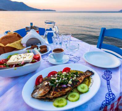 A fresh grilled Dorada fish served with Greek salad at a waterfront taverna in Ithaki during a sunset dinner.