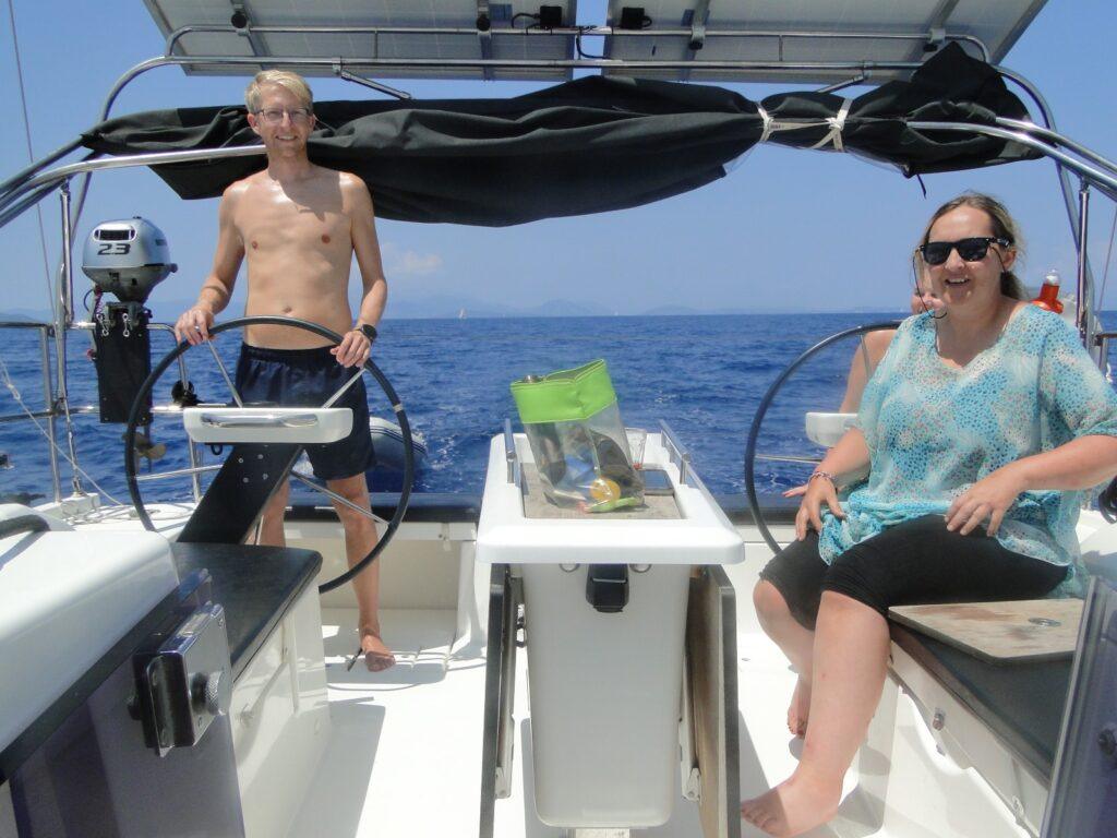 A happy guest at the helm during a Simply Sailing holiday in Greece for the 2026 season