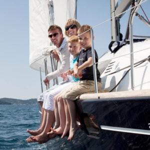 A familyrelaxing on the deck netting of a luxury catamaran during a skippered charter in Greece