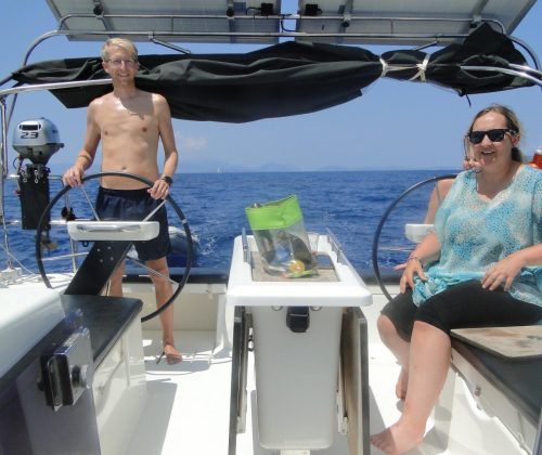 A happy guest at the helm during a Simply Sailing holiday in Greece for the 2026 season